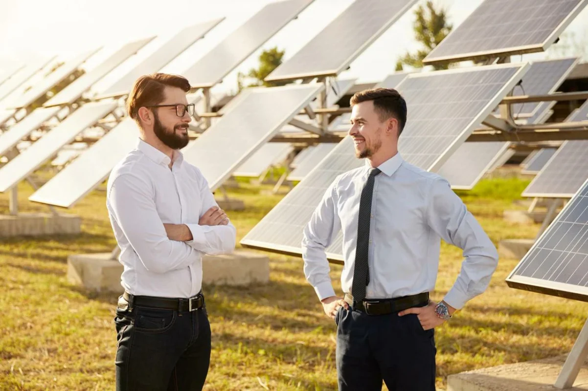 Due uomini in abbigliamento formale discutono di progetti di energia solare in un impianto fotovoltaico.