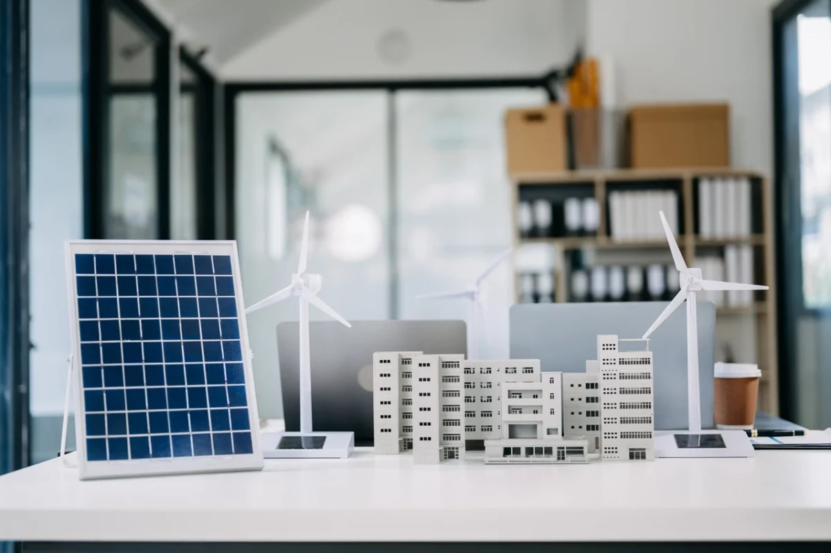 Modello di pannello fotovoltaico e turbine eoliche su scrivania, rappresentazione del progetto di energia rinnovabile per edifici