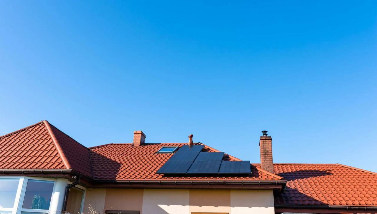 Pannelli solari neri eleganti installati sul tetto di una casa con tegole rosse, convertendo la luce solare in energia pulita per la gestione dei carichi domestici.