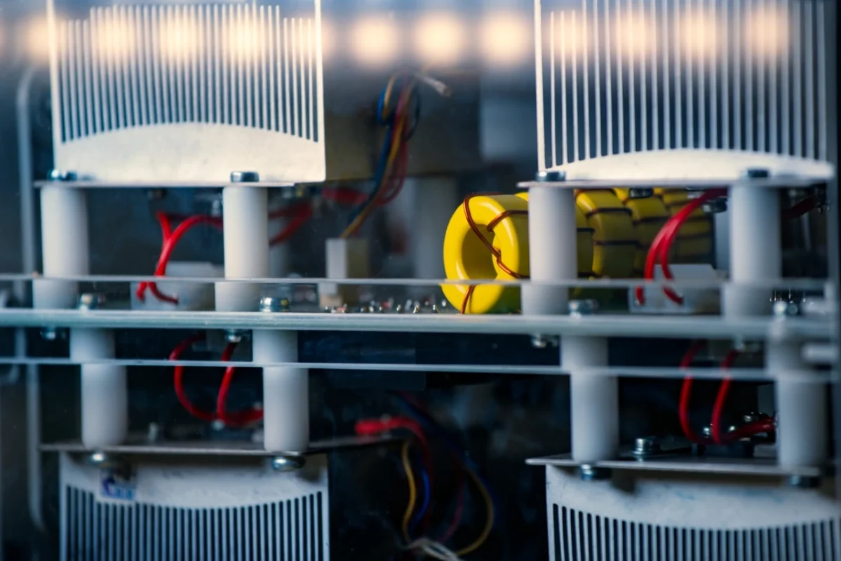 Circuito interno di un inverter solare con induttori toroidali e dissipatori di calore, utilizzato per la regolazione della potenza reattiva e la stabilità della rete.