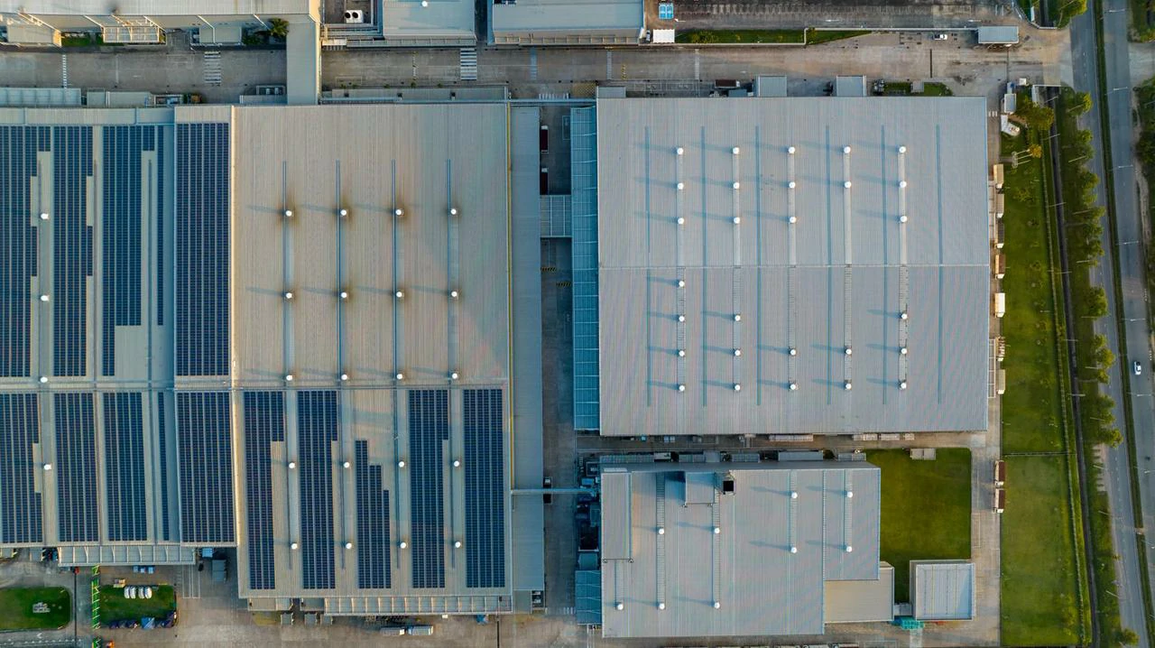 Vista aerea di pannelli fotovoltaici su un complesso industriale, ottimizzando l'uso dello spazio e il ritorno sull'investimento.
