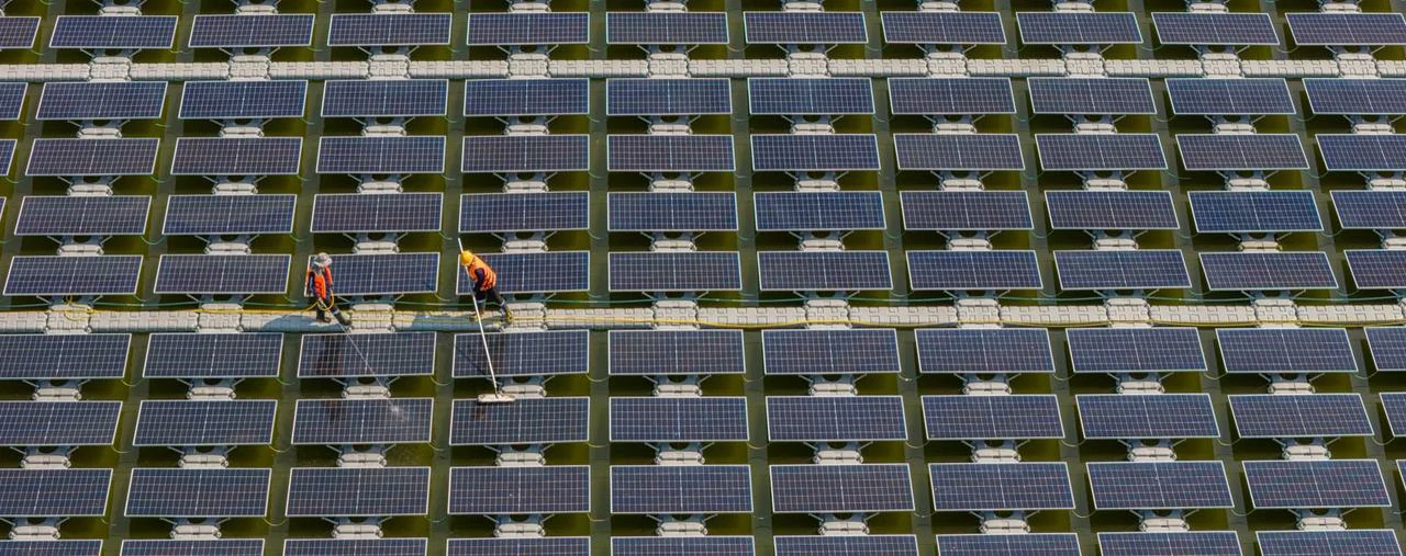 Operai puliscono i pannelli fotovoltaici galleggianti come parte della manutenzione predittiva.