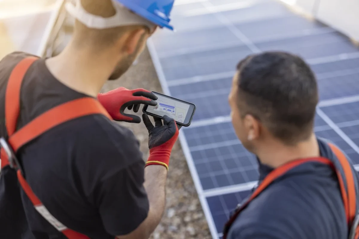 Due tecnici analizzano i dati di un impianto fotovoltaico, valutando i benefici degli incentivi per le imprese.