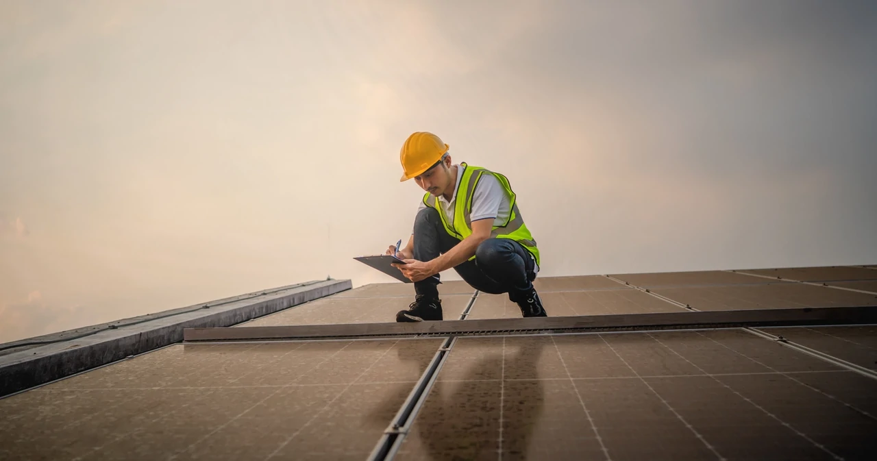 Un ispettore documenta i dati su un blocco appunti durante la verifica post-installazione di un impianto fotovoltaico.