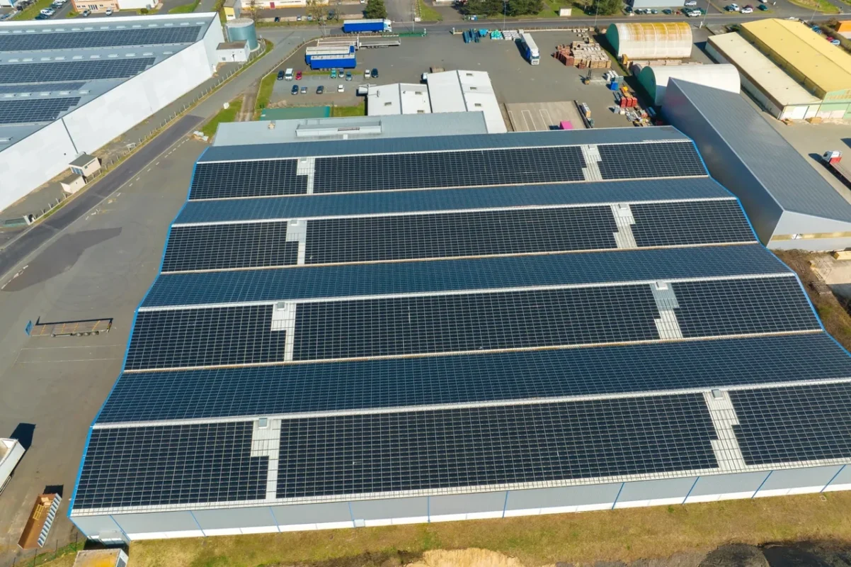 Vista aerea di pannelli fotovoltaici su tetto industriale, mostrando l'installazione gestita da distributori di inverter.