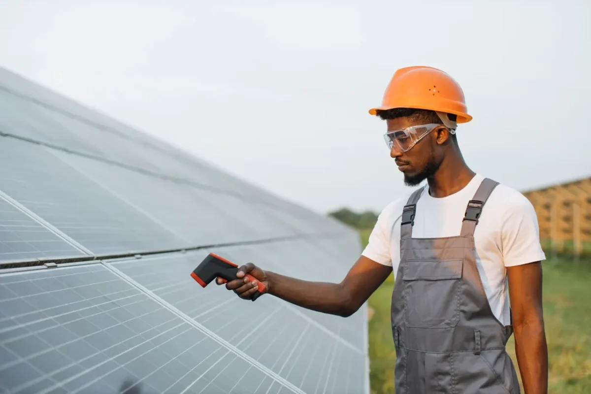 Tecnico con termometro ispeziona i pannelli PV, verificando l'efficienza dell'impianto per un agriturismo.