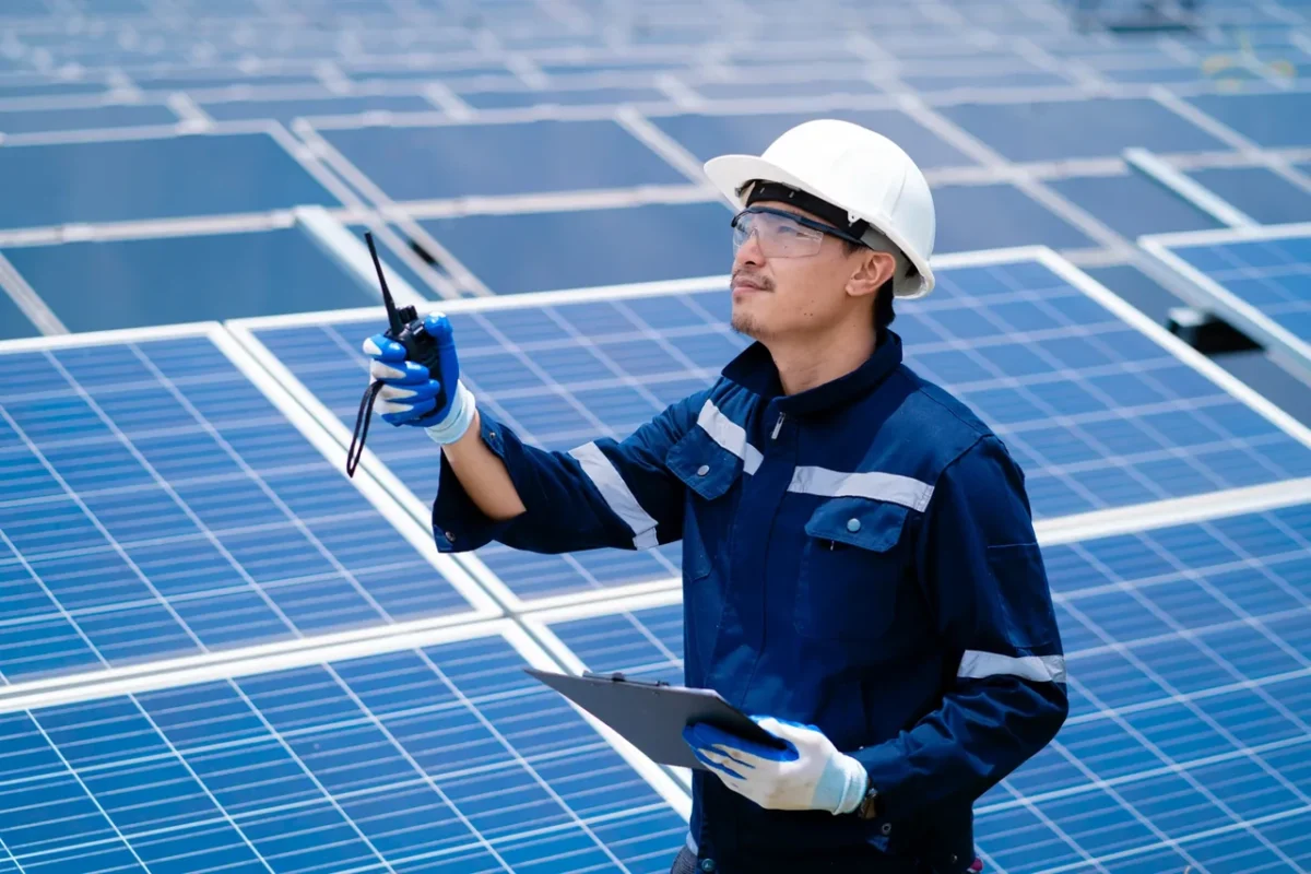 Tecnico con walkie-talkie ispeziona i pannelli PV, rappresentando il supporto tecnico offerto dai distributori di inverter.