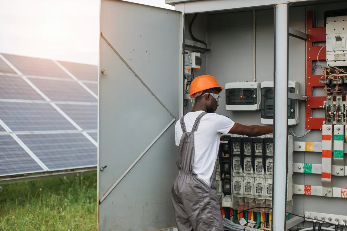 Tecnico che ispeziona il quadro elettrico di un impianto solare all'aperto.
