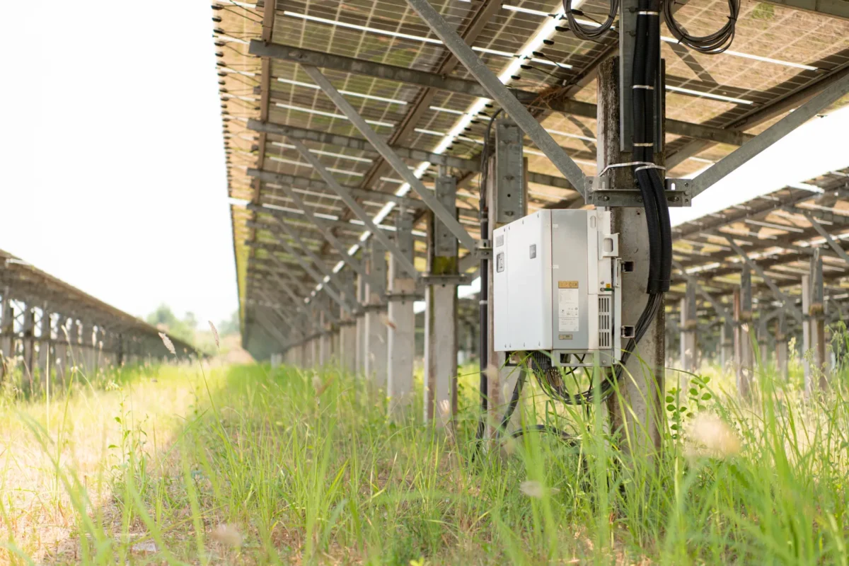 Un inverter professionale è installato su una struttura di un impianto fotovoltaico a terra.