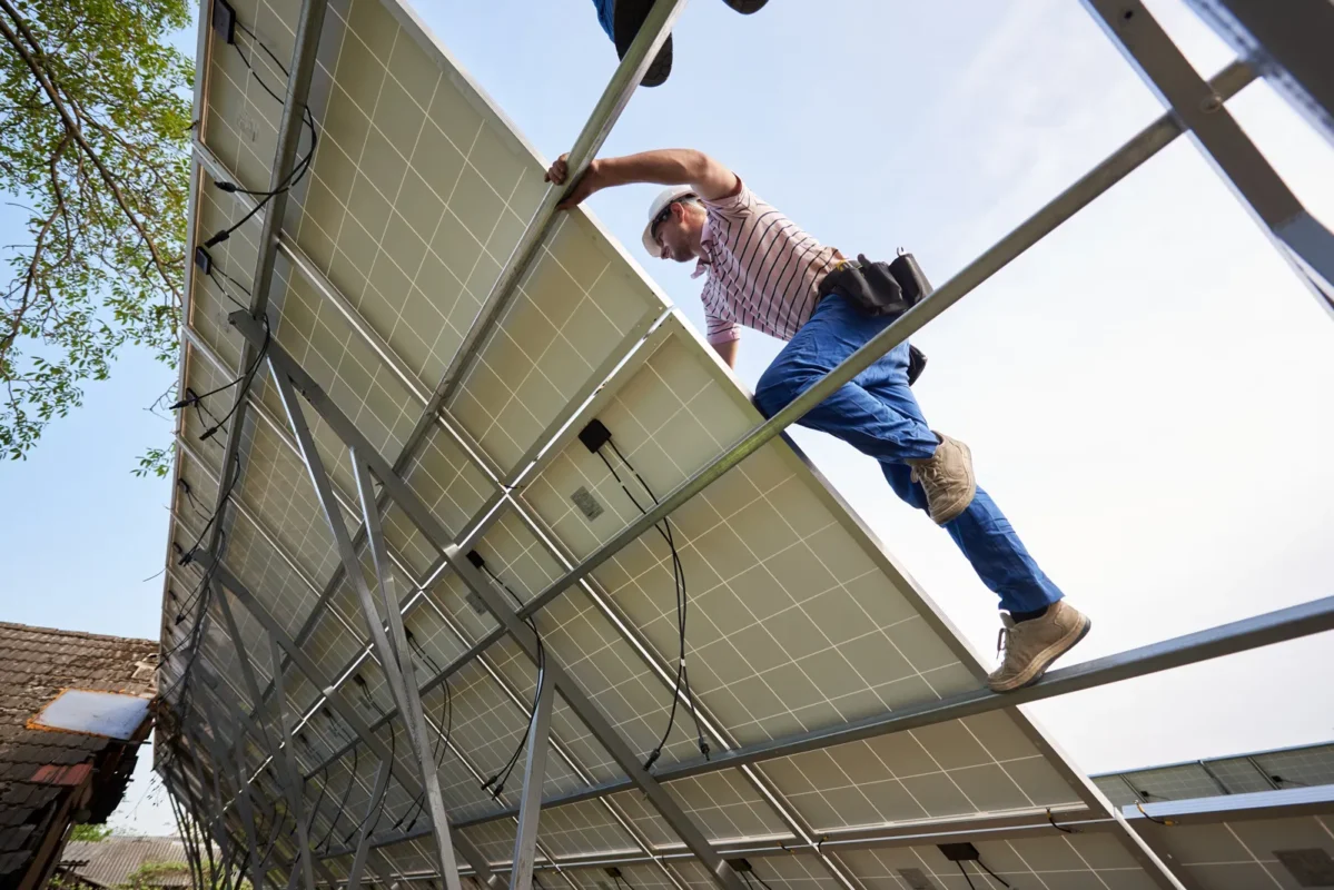 Operaio installa moduli fotovoltaici su struttura di supporto in un impianto solare.
