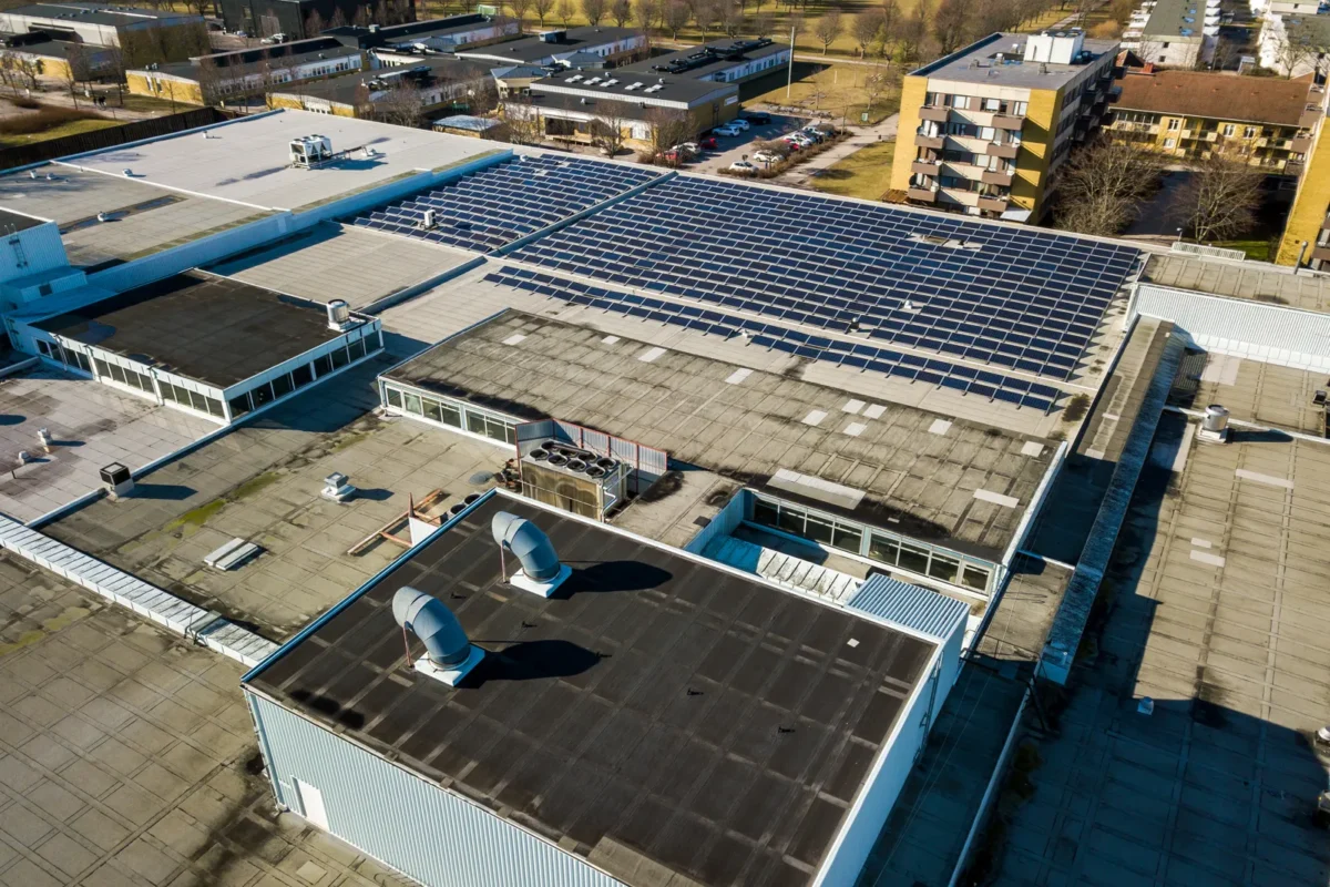Vista aerea di un impianto fotovoltaico industriale installato sul tetto di un edificio commerciale.
