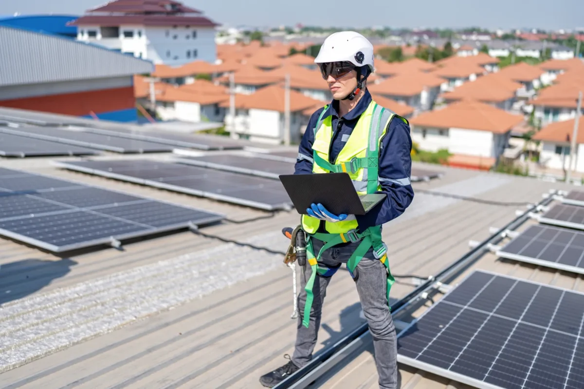 Tecnico specializzato verifica e gestisce un impianto fotovoltaico industriale con laptop.