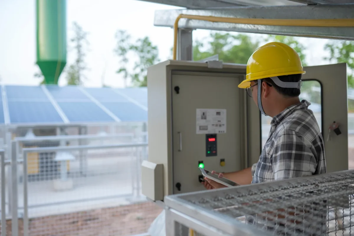 Tecnico verifica il quadro elettrico di un impianto fotovoltaico industriale.