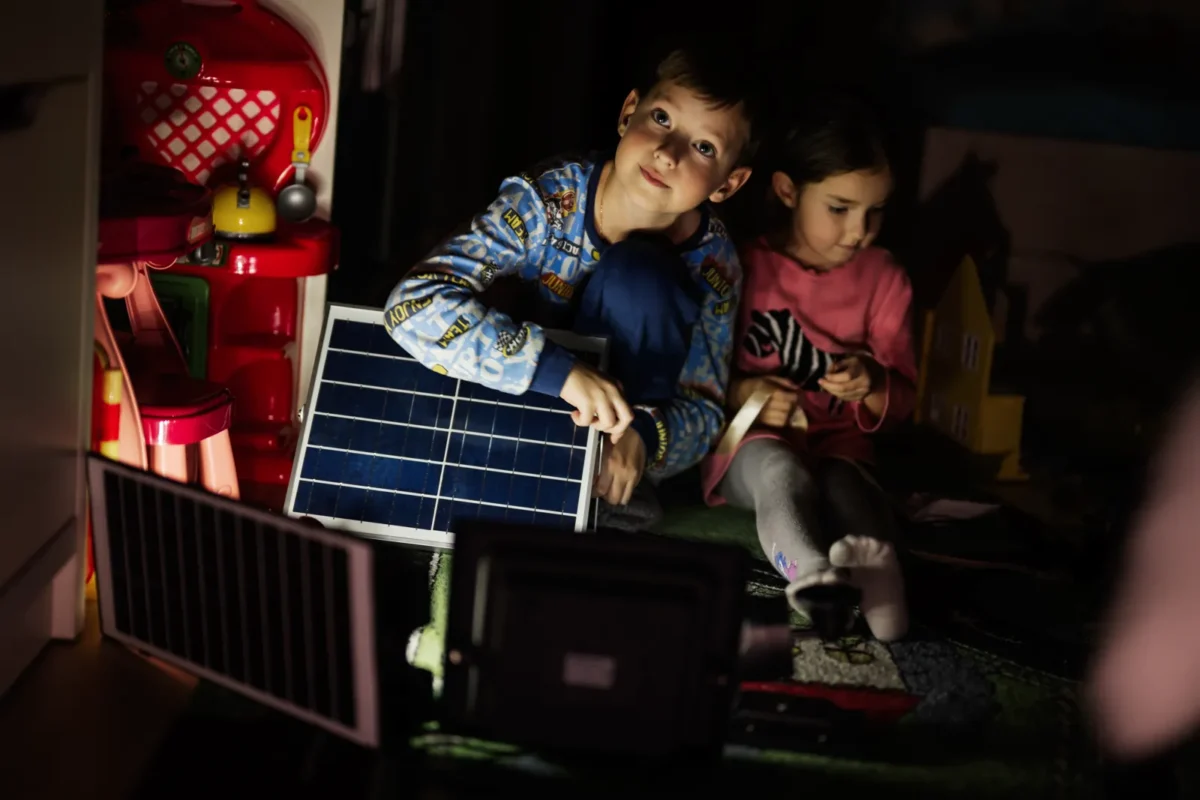 Bambini usano pannelli solari per l'illuminazione in una casa senza corrente.