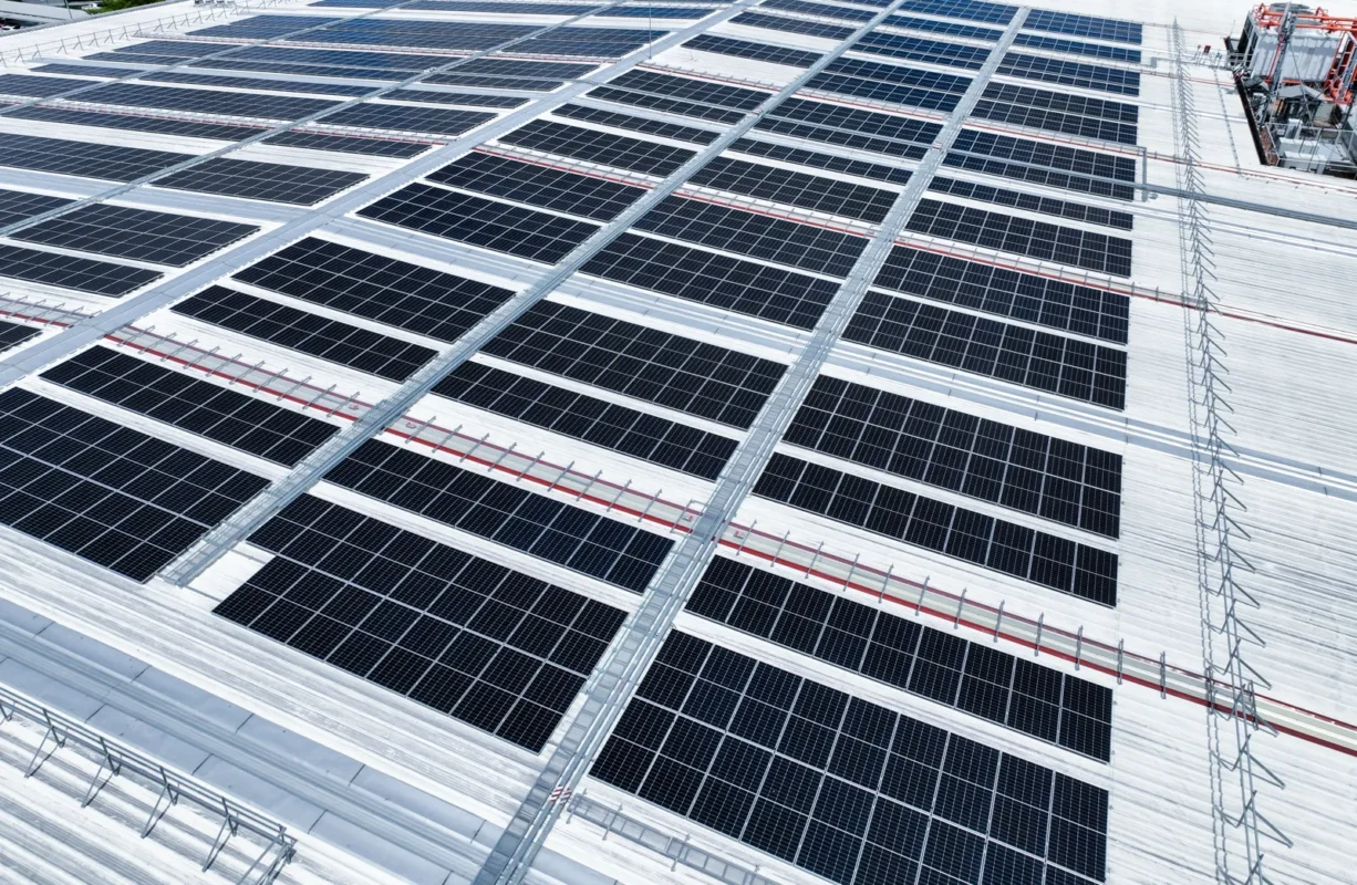 Vista aerea impianto fotovoltaico commerciale tetto capannone con moduli disposti in fila.