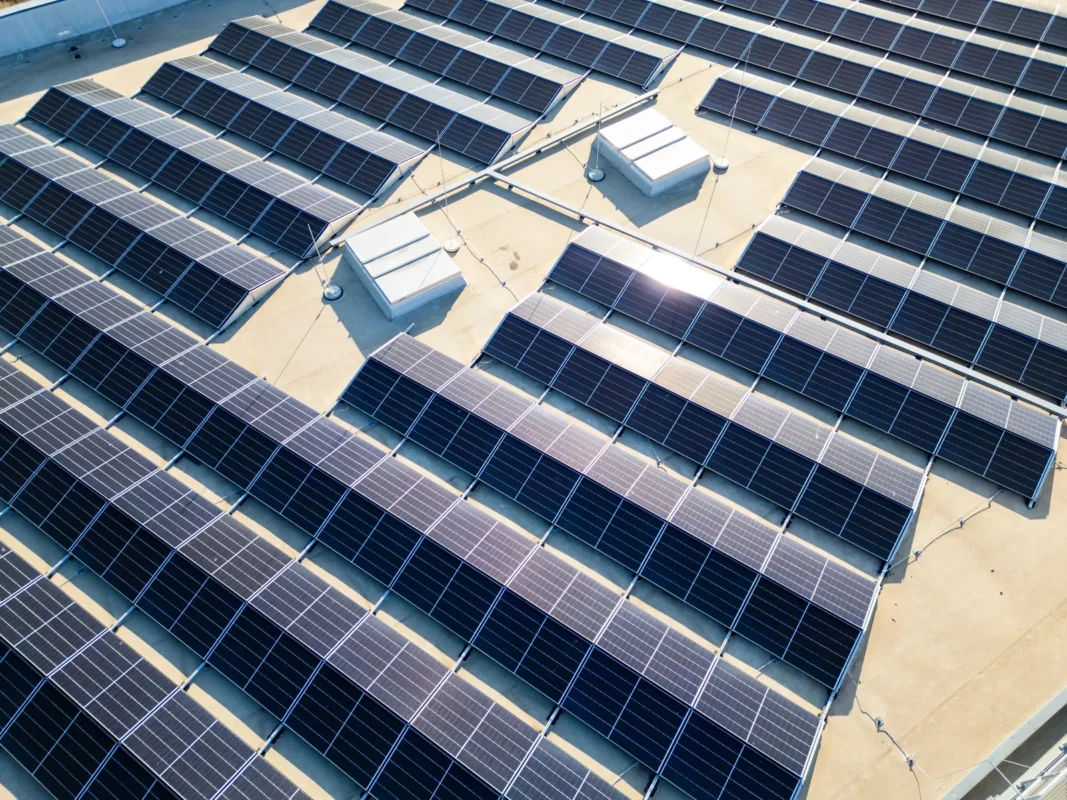 Aerial view of a large commercial rooftop solar panel array for string inverter systems.