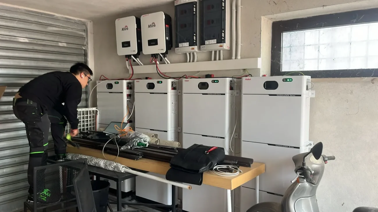 Technician installing multi-MPPT hybrid inverters and battery storage units in a facility.