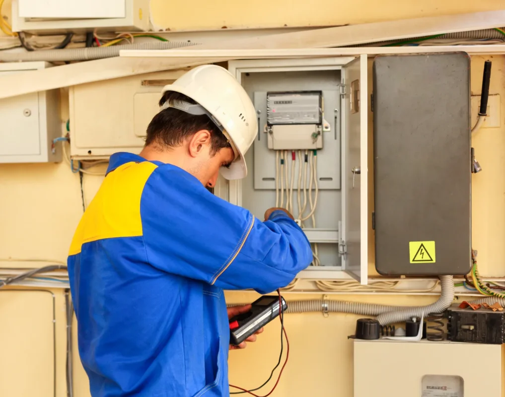 Technician testing wiring in an electrical box during off-grid solar inverter commissioning