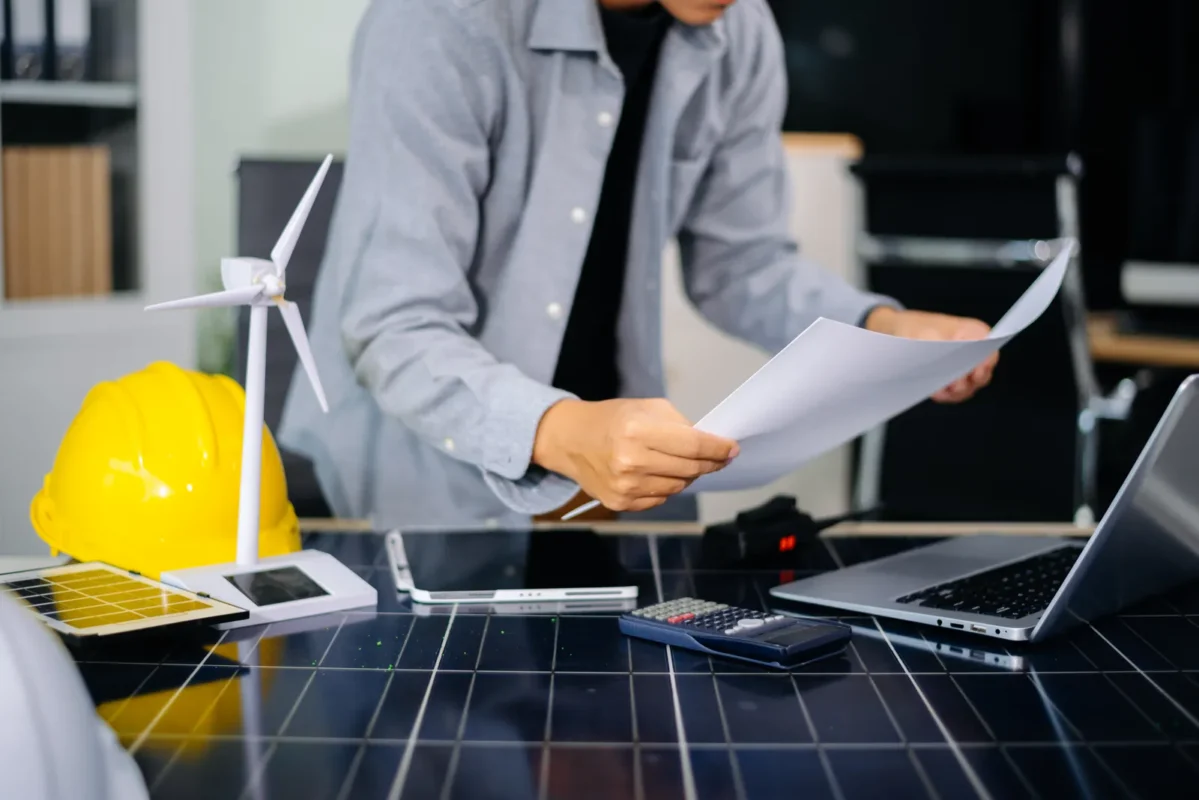 Engenheiro analisando plantas de projetos de energia solar para instalações B2B em edifícios residenciais multifamiliares, em um ambiente de escritório.