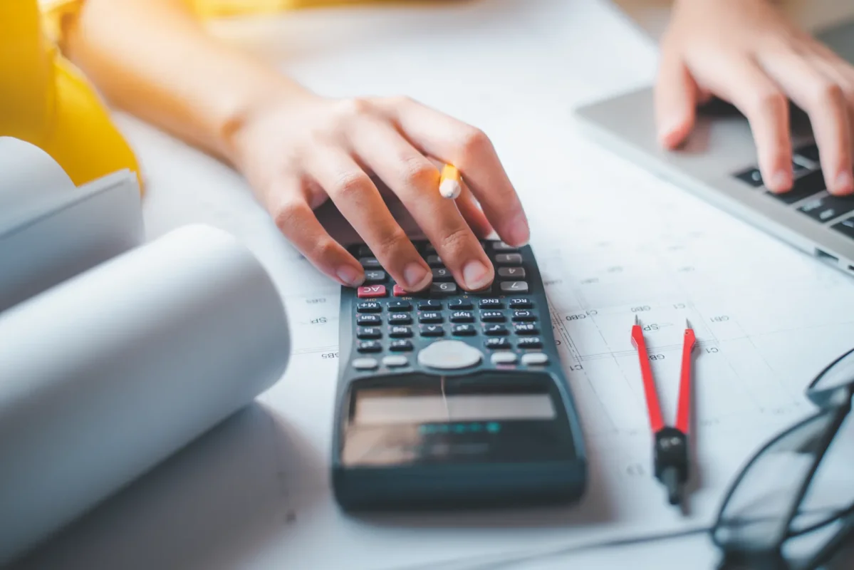 Engineer using a calculator to model costs and incentives for a commercial solar-plus-storage project.