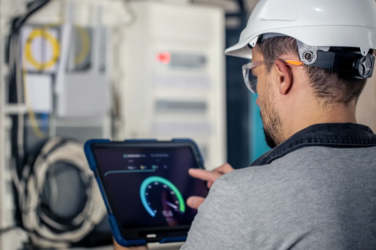Technician monitoring fanless solar inverter performance for C&I PV systems on a tablet