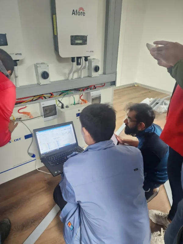  A group of technicians uses a laptop to debug parameters and test the running status of wall-installed Afore hybrid inverter chargers on-site.