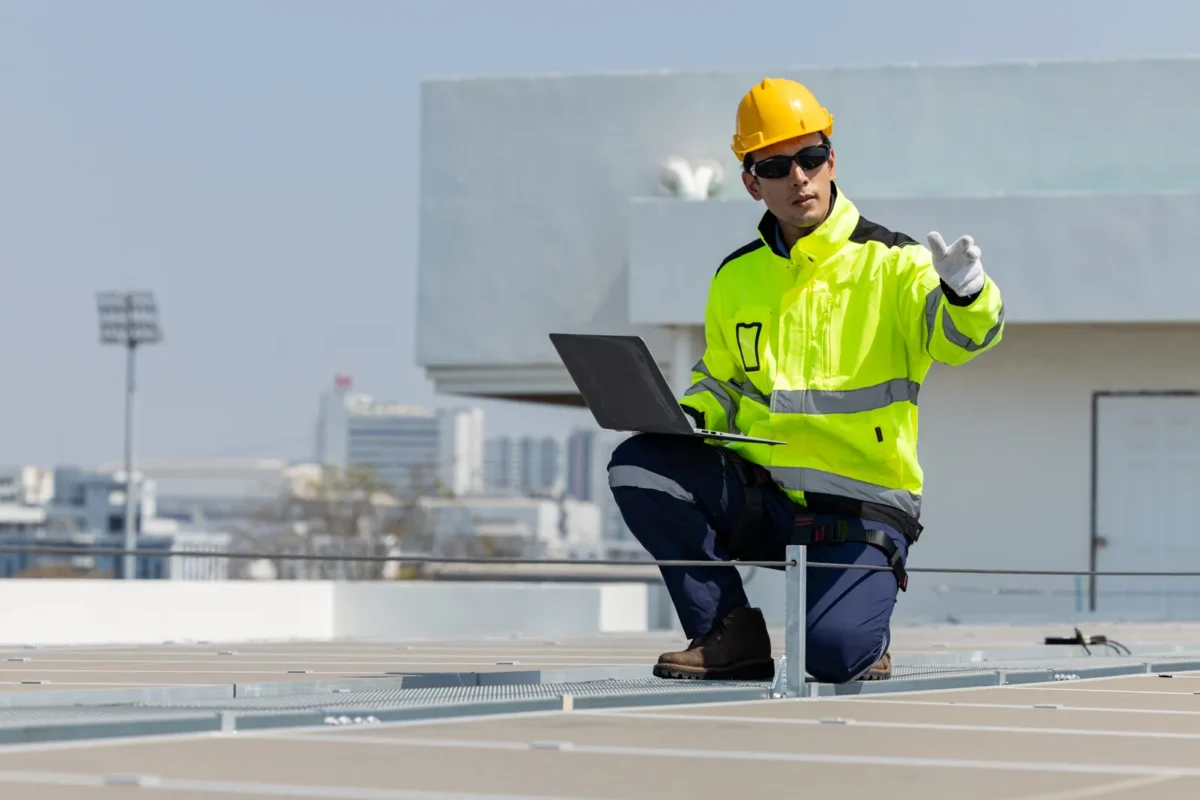 Engineer inspecting rooftop solar panels, key for evaluating hybrid vs microinverter B2B solutions.