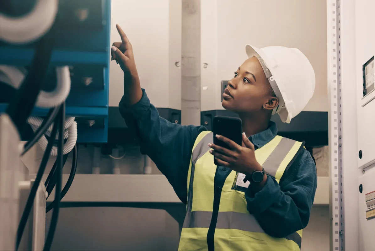 Female technician in safety gear inspects and commissions industrial battery storage equipment on-site.