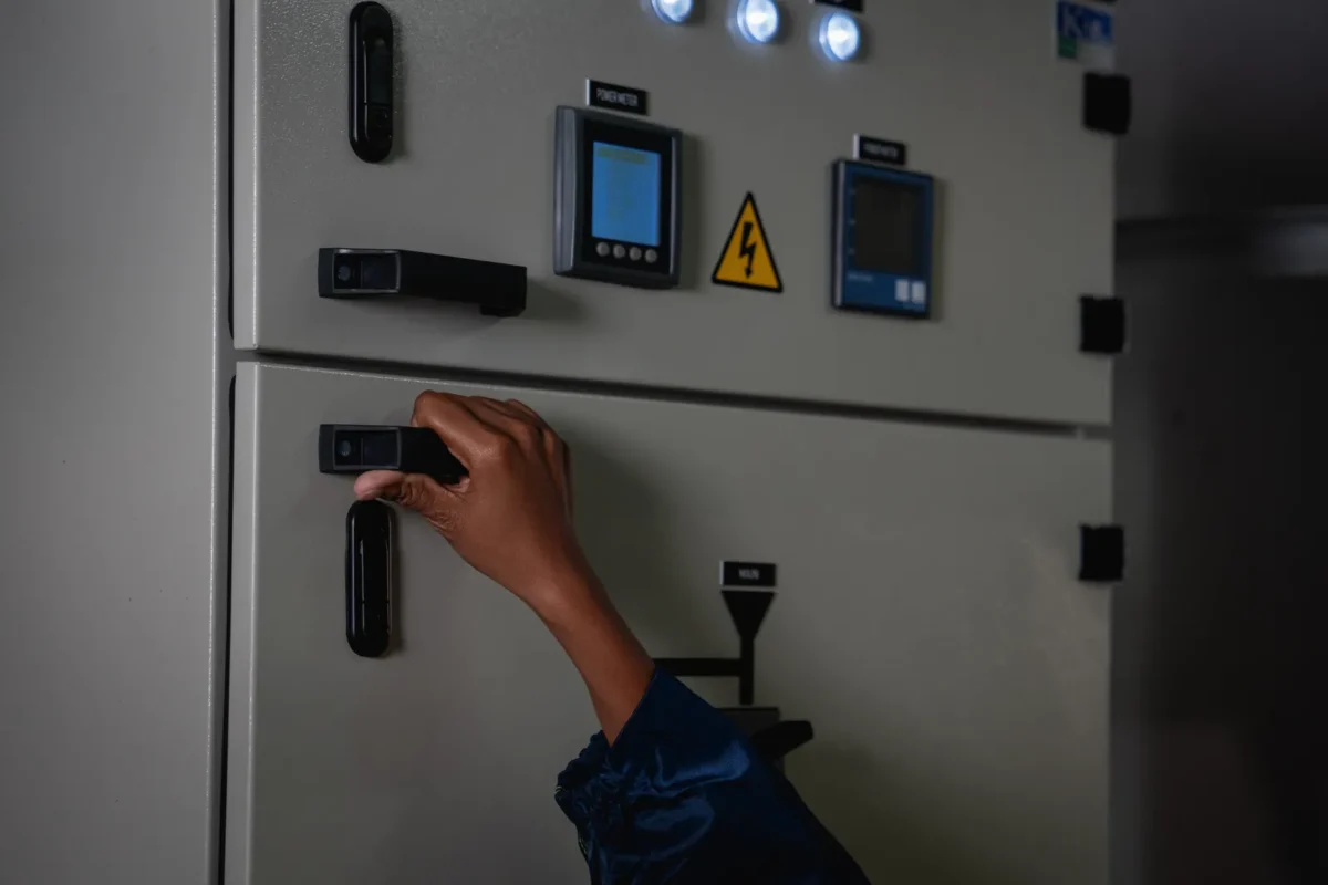 Technician’s hand opens the door of industrial power cabinet housing monitoring modules for 48V LiFePO4 battery and inverter energy storage systems.