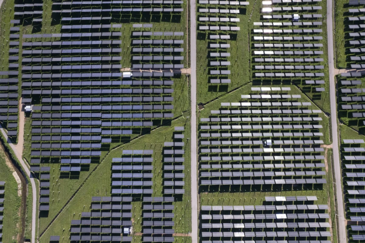 Aerial overhead shot of a large ground-mounted solar farm, the photovoltaic generation source feeding both AC coupled and DC coupled battery storage setups.