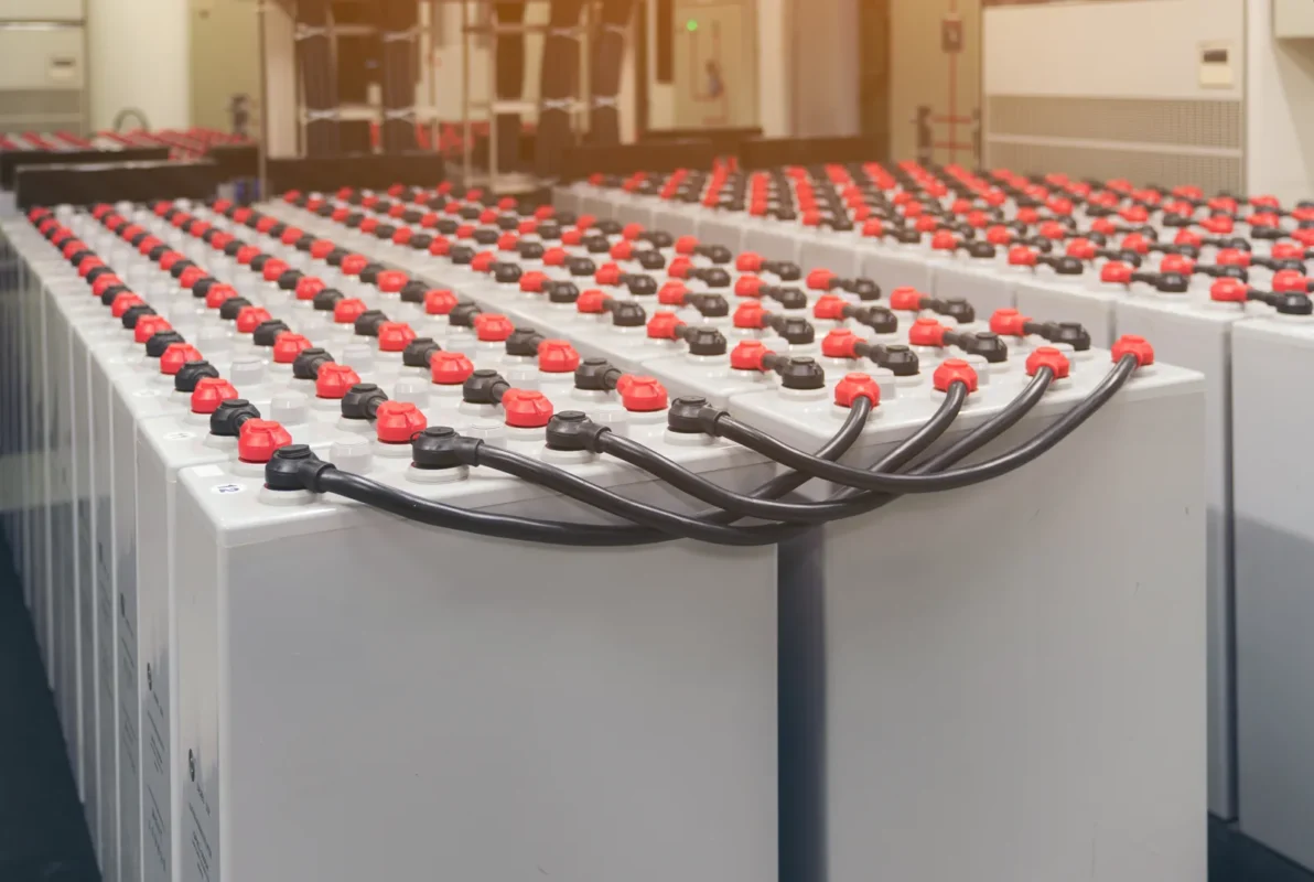 Rows of large lead-acid battery modules interconnected with thick cables forming the core power bank of commercial building battery storage installations.