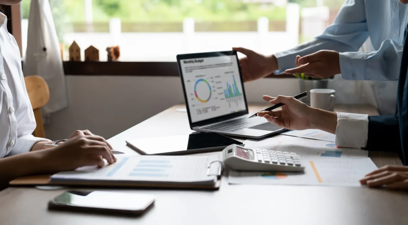 Business team analyzes monthly energy production charts on laptop to calculate ROI for commercial energy storage system investment projects.